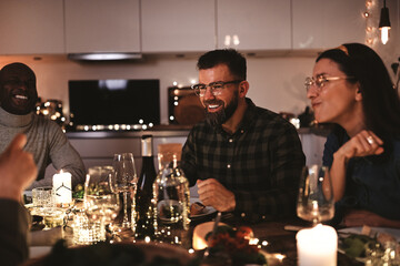 Laughing group of diverse friends enjoying a candlelit dinner party