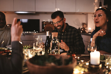 Diverse group of laughing friends enjoying a candlelit dinner party