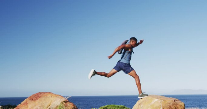 African american man exercising outdoors jumping on rocks in countryside on a mountain