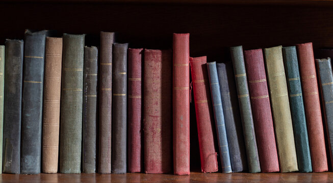 Old books on wooden shelf , colorful collection of antique books background