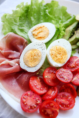 Boiled eggs, bacon, avocado, toast and tomatoes and lettuce salad.