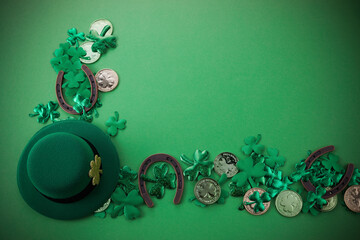 St Patricks Day border of shamrocks and gold coins and horseshoe over a green background. Top view,...