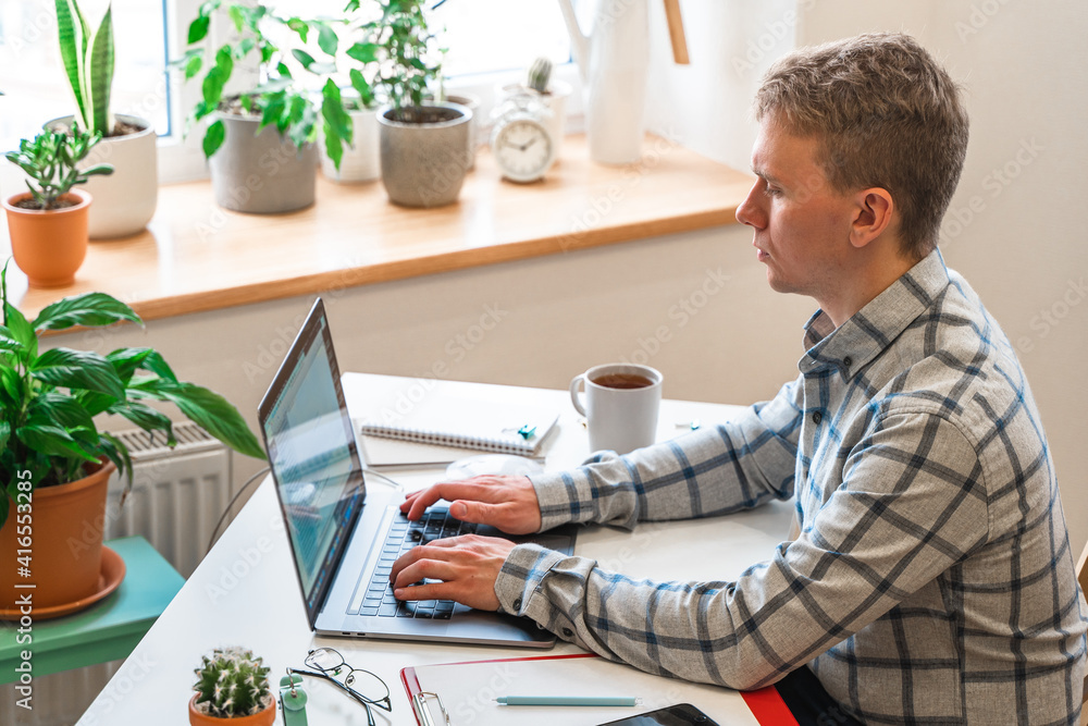 Canvas Prints a man in a shirt sits in a modern office and uses a laptop to work in business or programming, appli