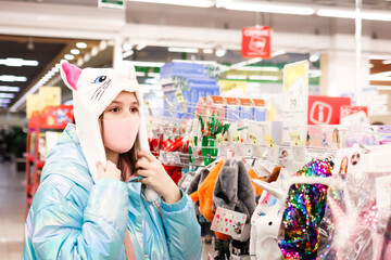 a cute teenage girl in protective medical mask choosing toys and gifts in the store