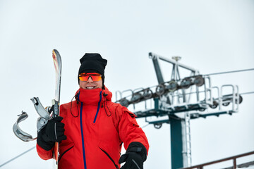 Male snowboarder in a red suit walking on the snowy hill with snowboard, Skiing and snowboarding...