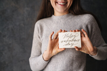 Caucasian smiling girl showing happy valentine's day card at camera