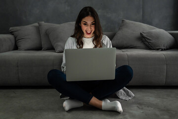 Happy smiling woman sitting on couch and using laptop