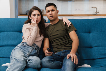 Obraz premium Photo of young scared couple watching tv