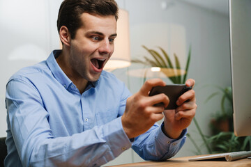 Happy young businessman using smartphone