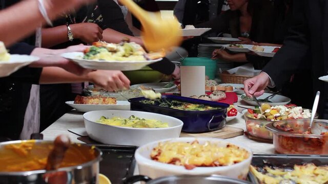 People Helping Themselves At A Buffet Like Potluck Sharing Food