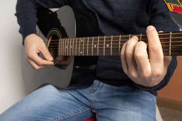 Fototapeta na wymiar young man playing black acoustic guitar on the white background