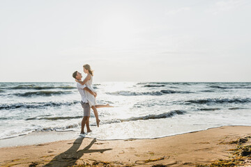 lovers near the ocean hug and have fun. husband and wife hugs at sunset near the sea. lovers on vacation. summer rest. romantic walk by the ocean