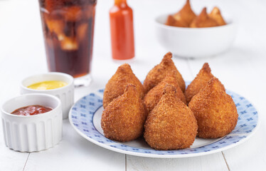 Typical brazilian snack coxinha on a plate with soda glass