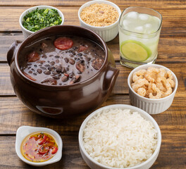Traditional brazilian feijoada with kale, rice, cracklings, manioc flour and caipirinha