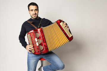 young man playing accordion on the white background - obrazy, fototapety, plakaty