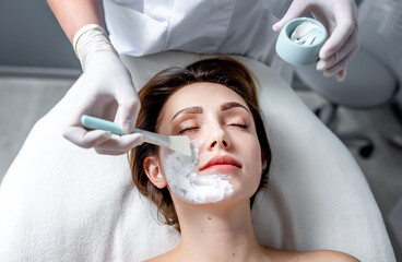 The imposition of a cosmetic mask on the face. A cosmetologist-dermatologist in a cosmetic clinic.