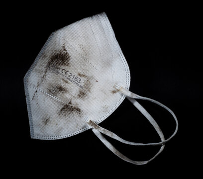 Sehr stark beschmutzte, unhygienische FFP2 Atemschutz Maske auf schwarzem Hintergrund.