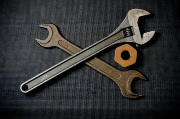 Old open-end and adjustable wrench on a dark background and a rusty nut. Renovation concept.