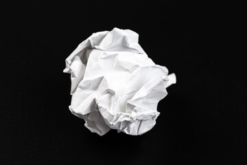 A crumpled paper ball in a black background