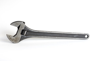 Old large adjustable wrench on a white background