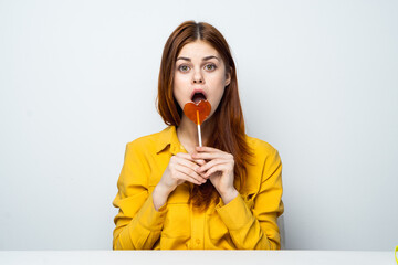 Cheerful pretty woman holding heart-shaped lollipop owner