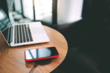 Charging mobile phone battery with wireless charging device in the table. Smartphone charging on a...