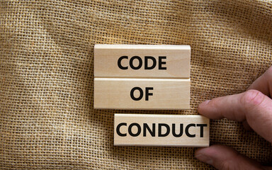 Code of conduct symbol. Concept words 'Code of conduct' on wooden blocks on a beautiful canvas background. Businessman hand. Business and code of conduct concept. Copy space.