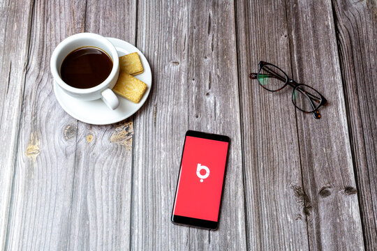 02-24-2021 Portsmouth, Hampshire, UK A mobile phone or cell phone on a wooden table with the Baaz social media app open next to a coffee and glasses