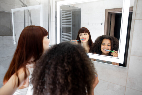 Mother and daughter brushing their teeth in bathroom at home