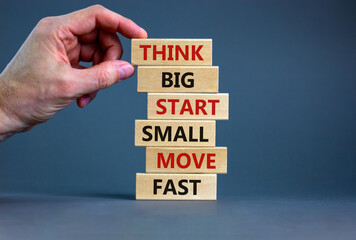 Think big start small symbol. Words 'Think big start small move fast' on wooden blocks on a beautiful grey background. Businessman hand. Business, motivational and think big start small concept.