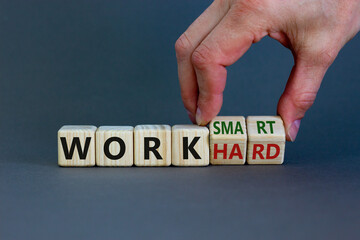 Work hard or smart symbol. Businessman turns wooden cubes and changes words 'work hard' to 'work...