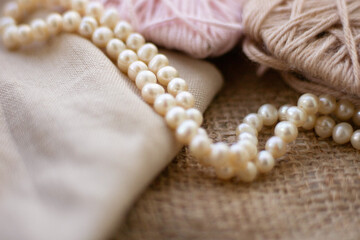 Cuts of yarn and thread on the background of burlap. Beige and soft pink colors of woolen and...
