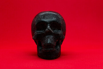 A skull made of wax on a red background.