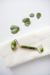 green jade facial massage roller on white towel, facial spa, home care
