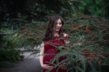 Pregnant woman resting in spring blooming garden. Posing outdoors. Motherhood. High quality photo.