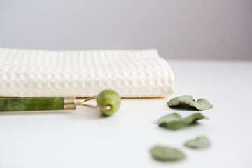 green jade facial massage roller on white towel, facial spa, home care