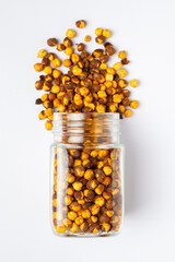 Crunchy Roasted Chana Masala spilled out and in a glass jar, made with Bengal Grams or Chickpeas....