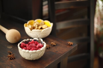 Maliny w ceramicznej miseczce na drewnianym stole © Seance_Photo_Sylwia