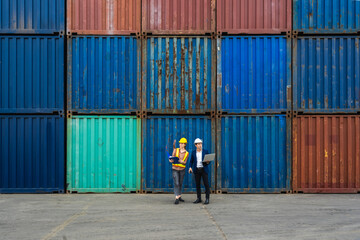 two engineer worker hold a laptop, document for checking a quality of containers box from cargo...