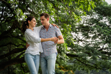 Fototapeta premium Young couple having fun in the moment of love in the park. Love and tenderness, Romantic man playing guitar to his girlfriend, lifestyle concept