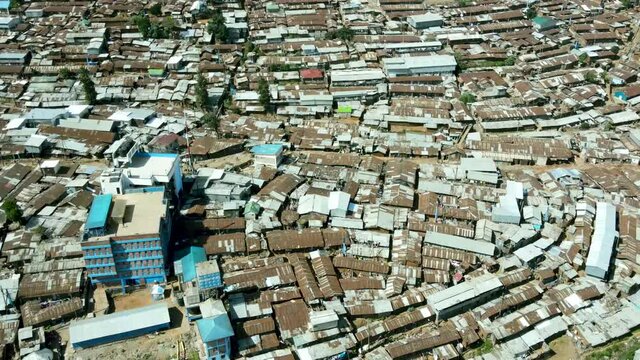 Aerial tilt up shot of crowded urban slum area in Kibera and modern skyline of Nairobi in background during sunlight. Kenya,Africa. Poverty and Wealth on earth.
