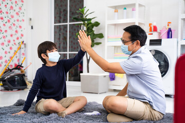 Father puts on son medical face mask in home Coronavirus quarantine and epidemic, Family wearing face mask for protection during the quarantine