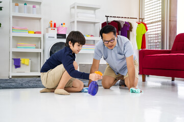 Happy family cleans the room. Asian father and son do the cleaning in the house. A young man and child girl are dusting, washing floor with towel and spray in living-room