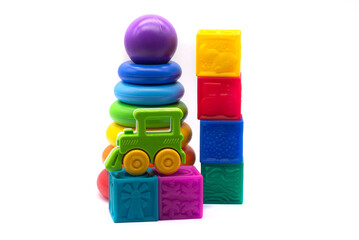 Children's multi-colored pyramid, plastic steam train and rubber cubes on a white background
