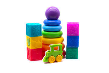 Children's multi-colored pyramid, plastic steam train and rubber cubes on a white background