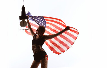 A patriotic young teenage girl is seen in front
of a white background. She proudly waves the 
American flag around her in a cheerful manner.