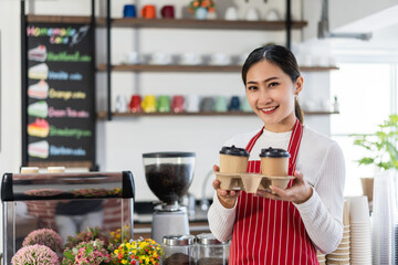 Portrait of woman owner standing at her coffee shop gate holding a cup of coffee