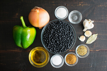 Cuban Black Beans (Frijoles Negros) Ingredients: Black turtle beans with other raw ingredients on a dark wood background