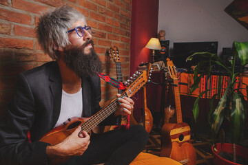 Obraz premium Portrait of bearded man men's jacket barefoot whit acustic guitars sitting of a bed