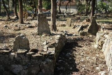 Tombstones at the old graveyard. Old cemetery with ruined weathered headstones. Sunny summer day.